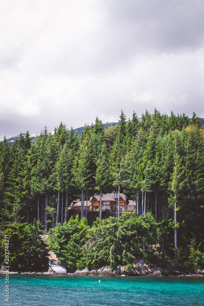 Naklejka premium House hidden in the middle of the woods, with a view of a lake in Bariloche, Patagonia Argentina
