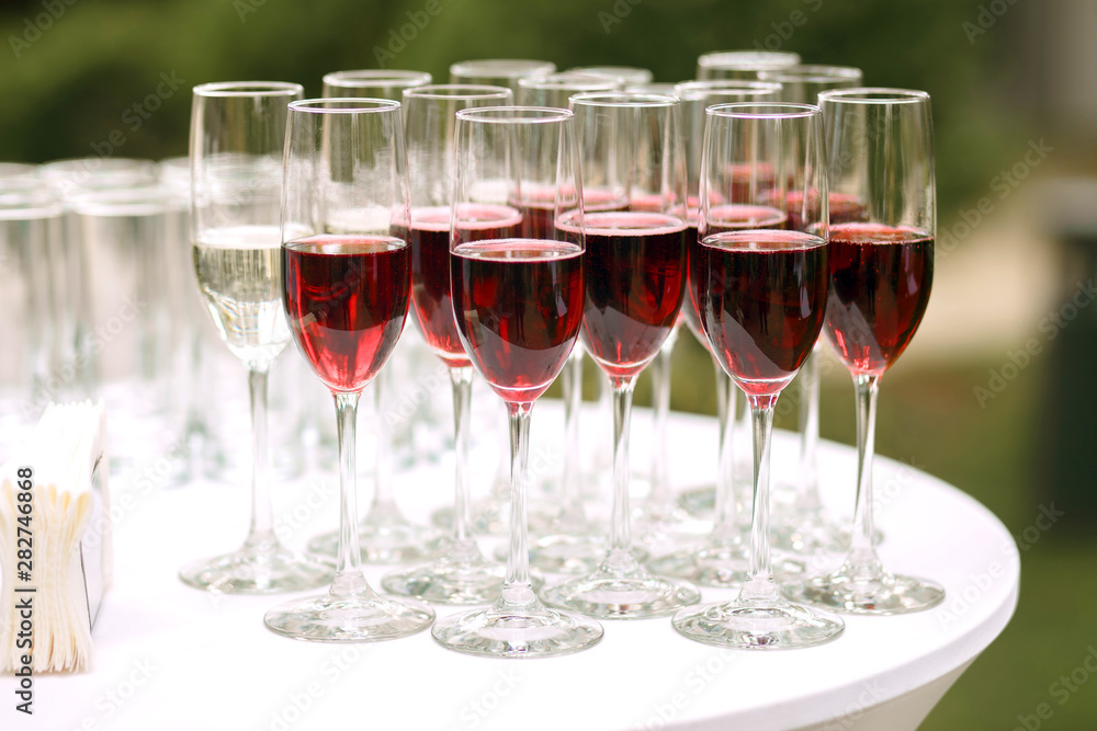 Lots of glass goblets with red wine at an outdoor party. Alcohol in the form of sparkling red wine