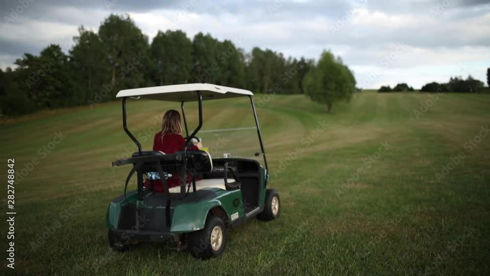 Young woman have a fun with golf buggy car on a field in mountains, Czech Young woman have a fun with golf buggy car on a field in mountains, Czech