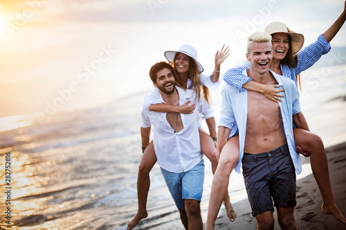 Group of people running on beach and enjoying summer holiday