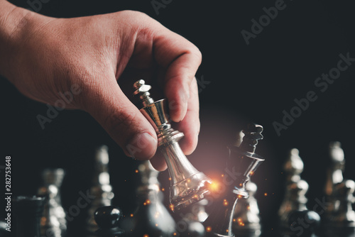 hand of businessman moving chess figure in competition success play. strategy, management or leadership concept