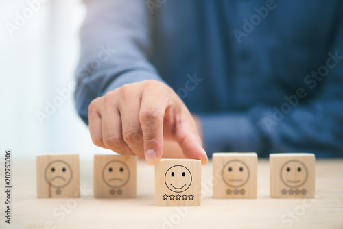 Close up customer hand choose smiley face and blurred sad face icon on wood cube, Service rating, satisfaction concept.. business development Decide and choose concept.copy space.