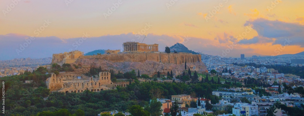 Parthenon temple in Acropolis Hill, Athens, Greece, shot in blue hour over old town during colorful sunset with pink and purple clouds in the sky. Lycabettus Hill on background panorama Europe travel.