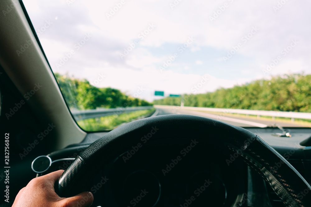 Inside view, hand of a driver on steering wheel of a car with empty asphalt road background. High-quality free stock image of driver hands on the steering wheel inside. Summer trip or vacation by car Inside view, hand of a driver on steering wheel of a car with empty asphalt road background. High-quality free stock image of driver hands on the steering wheel inside. Summer trip or vacation by car
