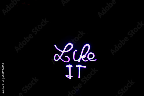 Words "like it" written with a led lamp during a lightpainting session at night. Abstract curved shape drawn with a light saber. Logo for button web. 
