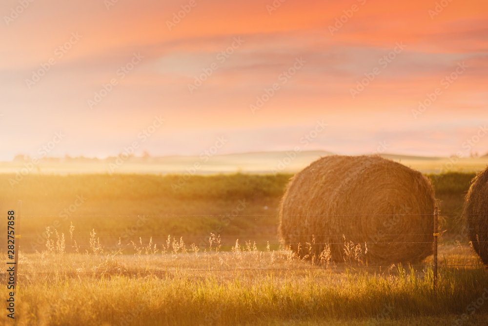 Round circular Bale of Hay in rural North Dakota in a field at sunset with an orange sky