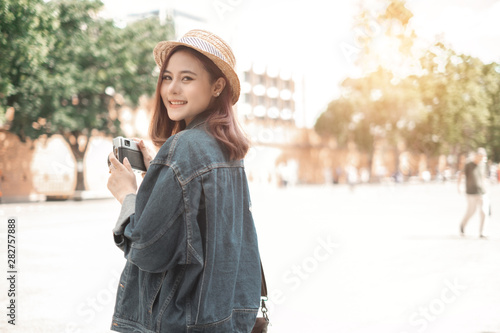 Smiling woman traveler with backpack holding vintage camera on holiday in thapae gate landmark chiang mai thailand,relaxation concept, travel concept
