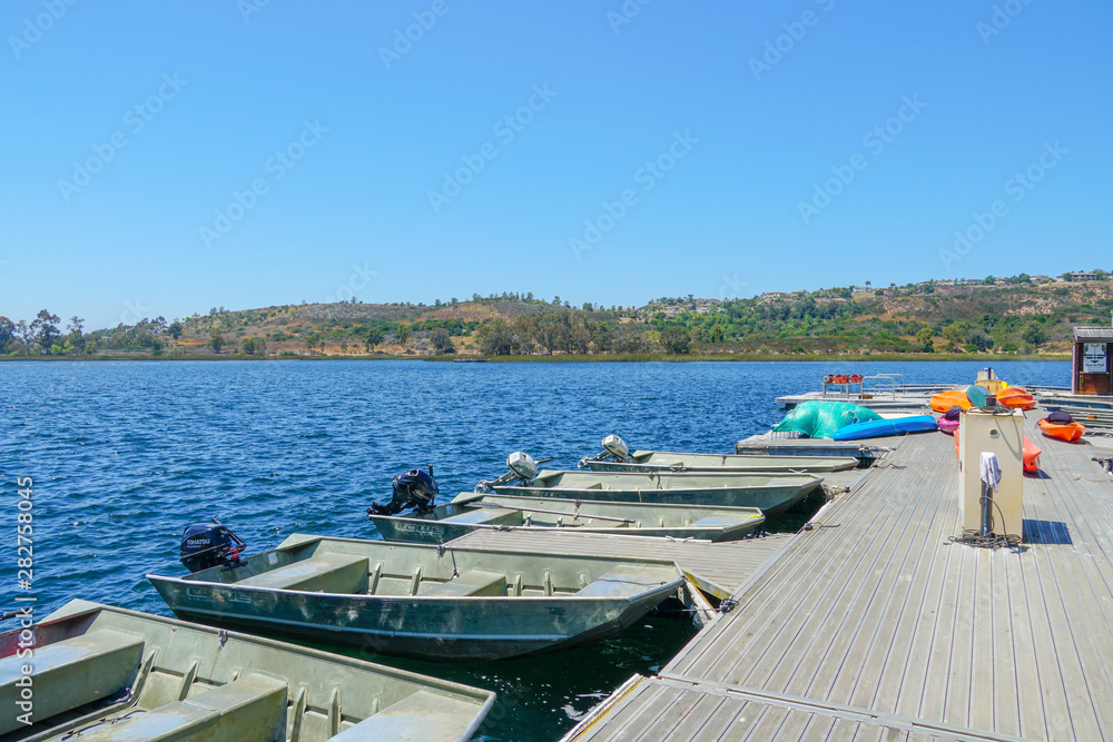 Small pier with pedal boat, small motor boat. Lake with popular activities including boating, fishing. Miramare Lake, San Diego, California, USA