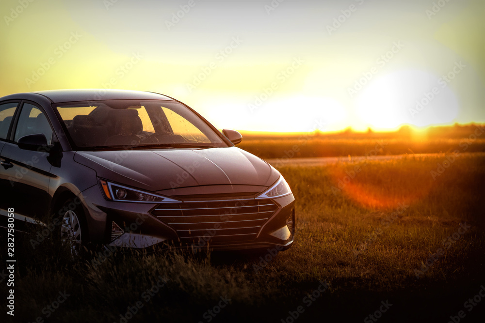 Late model new sedan parked in rural north dakota among farms and fields at sunset Late model new sedan parked in rural north dakota among farms and fields at sunset