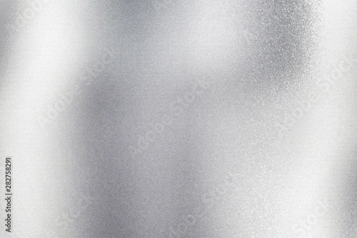 Glowing silver metal wall with scratched surface, abstract texture background