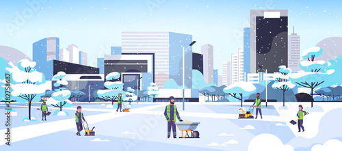 cleaners team using different equipment and tools snow removal concept men women in uniform cleaning winter snowy park cityscape background flat full length horizontal
