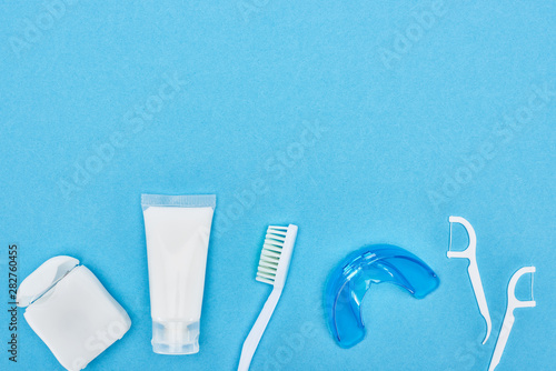 top view of toothpaste, toothbrush and teeth floss near retainer and floss toothpicks isolated on blue