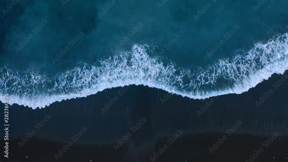 Top view of the desert black beach on the Atlantic Ocean. Coast of the island of Tenerife. Aerial drone footage of sea waves reaching shore