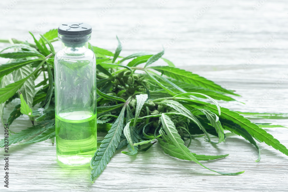 Cannabis essential oil in vial over a white table background. Cannabis essential oil in vial over a white table background.
