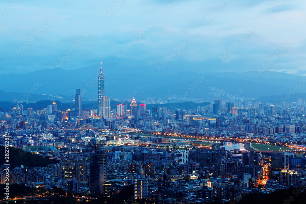 Sunset scenery of Downtown Taipei, vibrant capital city of Taiwan, with landmark  tower standing out amid high-rise buildings in Xinyi Financial District & colorful city lights dazzling in twilight