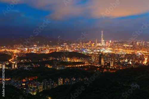 Sunset scenery of Downtown Taipei, vibrant capital city of Taiwan, with landmark tower standing out amid high-rise buildings in Xinyi Financial District & colorful city lights dazzling in twilight