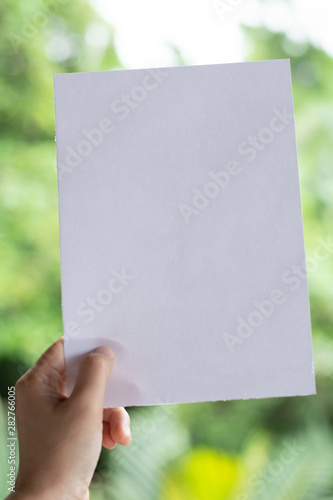 Woman holding paper blank of drawing paper paper with natural background.