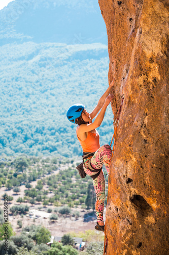 A girl in a helmet climbs a rock.