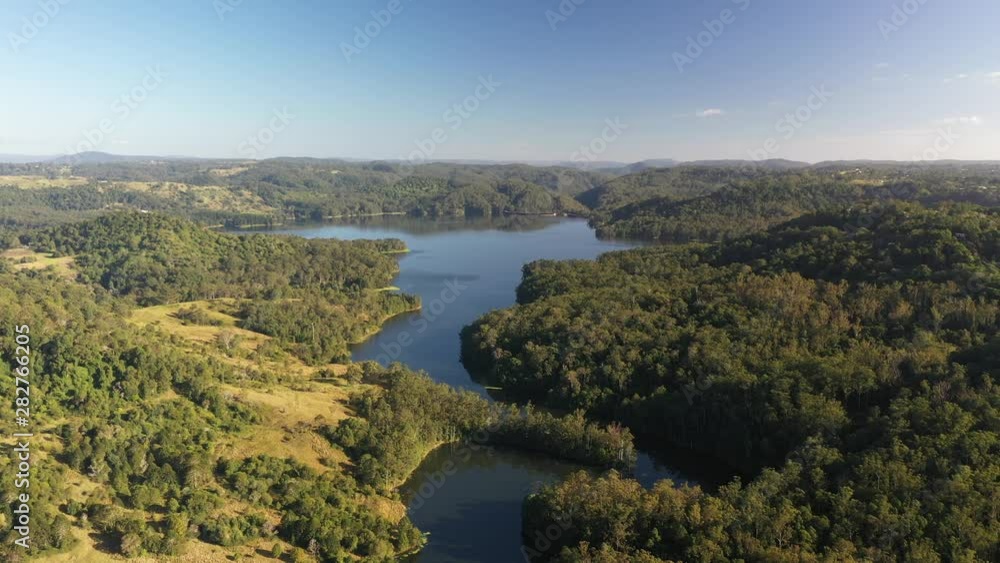 Aerial shot of a lake reservoir of water with forest surrounding it at sunrise in Queensland, Australia. Water consumption, global warming and severe drought affect the water level and reserve. Aerial shot of a lake reservoir of water with forest surrounding it at sunrise in Queensland, Australia. Water consumption, global warming and severe drought affect the water level and reserve.