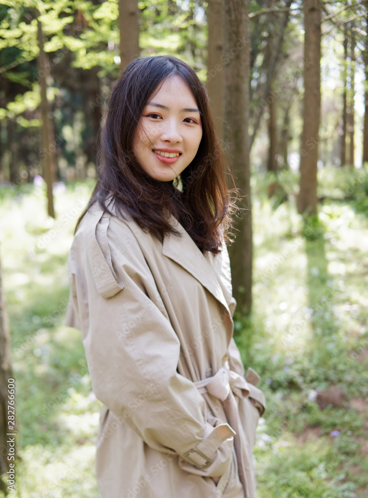 Beautiful young brunette woman posing and smiling in forest park. Outdoor fashion portrait of glamour Chinese stylish lady with black long hair. Emotions, people, beauty and lifestyle concept. Beautiful young brunette woman posing and smiling in forest park. Outdoor fashion portrait of glamour Chinese stylish lady with black long hair. Emotions, people, beauty and lifestyle concept.