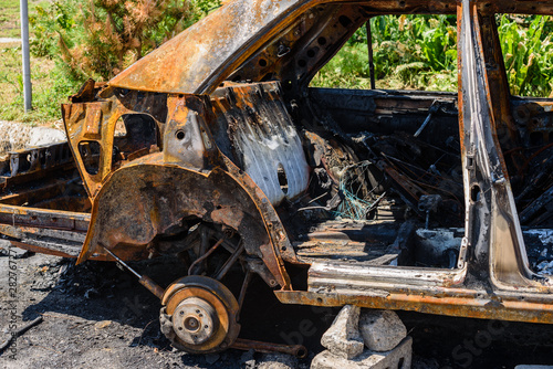 Burned car parked on the street  close-up. Abandoned burnt down car after an explosion  ready to be scrapped