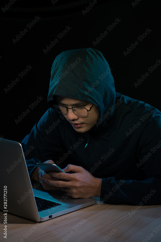 Hacker using a smartphone. Very dark nocturnal environment Hacker using a smartphone. Very dark nocturnal environment