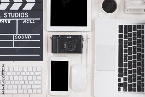 top view of film clapper and gadgets on wooden desk