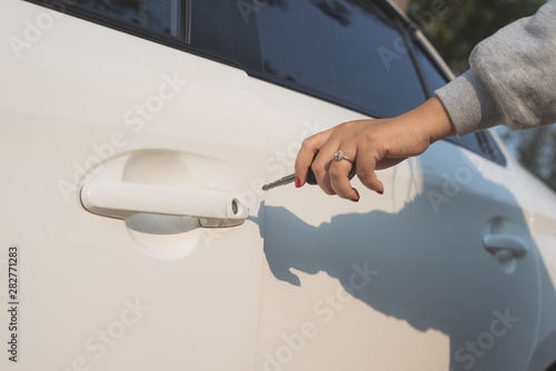 A hand opening a car door with a key