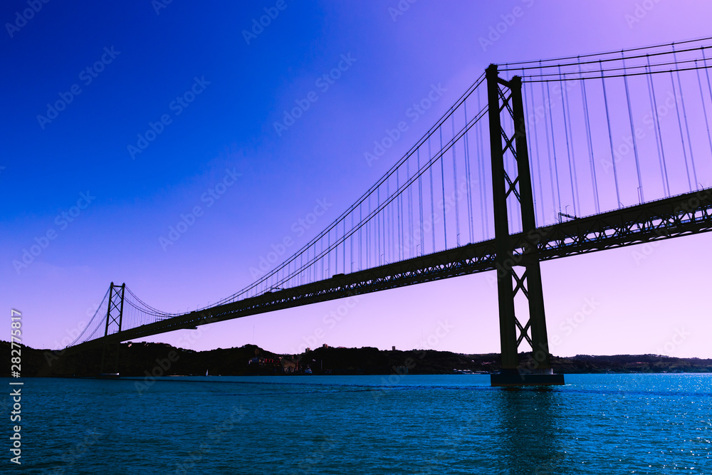 Silhouette of large metal bridge across the sea Strait on the background of a fantastic purple sky