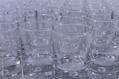 Transparent glass cups in a bar on a white background