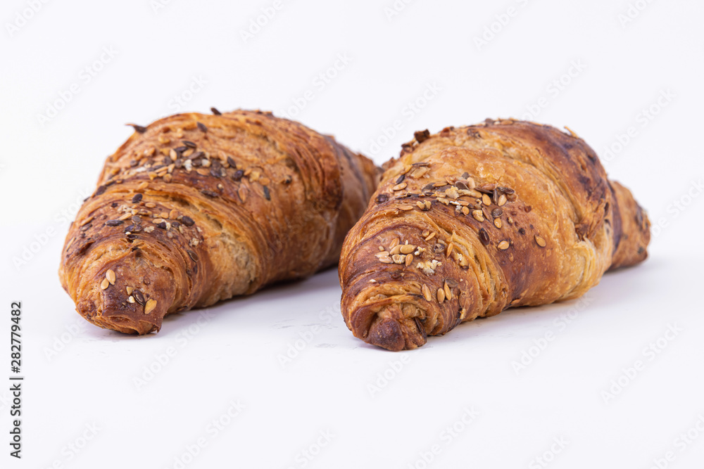Closeup of two croissants sprinkled with powdered sugar and sesame seeds Closeup of two croissants sprinkled with powdered sugar and sesame seeds