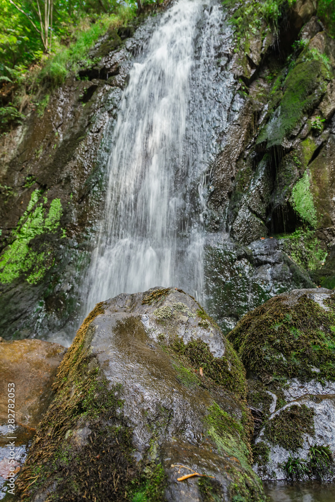 Fototapeta premium Nice waterfall from front with big stones, Novohradske mountain, Czech republic