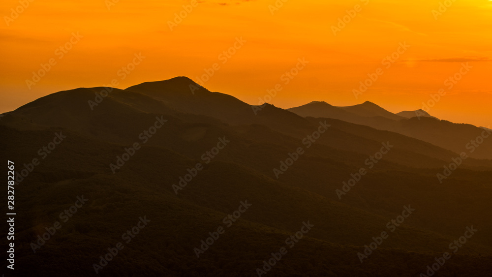 Stunning sunset in the mountains. Orange sky and mountains silhouettes. Carpathian Mountains. Bieszczady. Poland