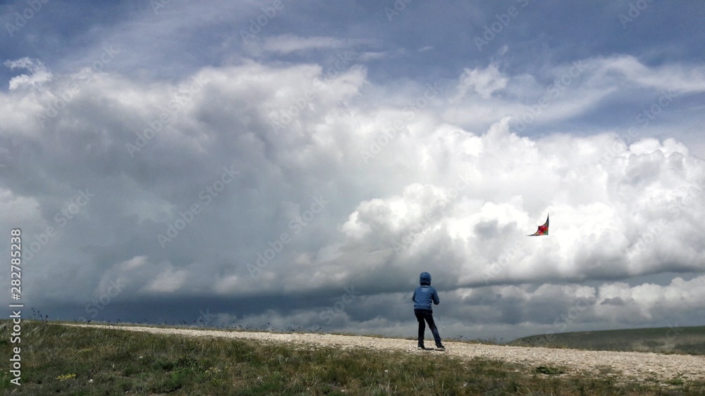 Boy launches a kite. Kite flying and storm clouds.