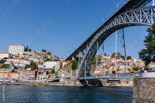 Porto, Portugal - 10/20/2019: Famous bridge Ponte Luis in Porto bottom view. Riverside near giant steel bridge with people and boats. Portuguese river Douro with metro bridge. Porto cityscape.