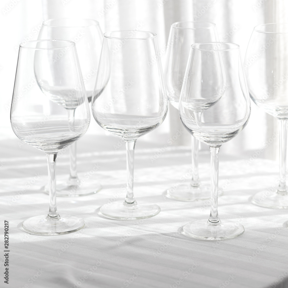 Several empty wine glasses in white grey shades on the white tablecloth for abstract background Several empty wine glasses in white grey shades on the white tablecloth for abstract background