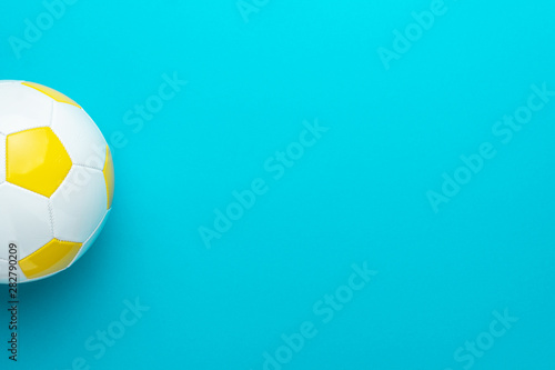 Top view of part of white and yellow soccer ball over turquoise blue background with copy space. Minimalist flat lay image of football ball as sport background.