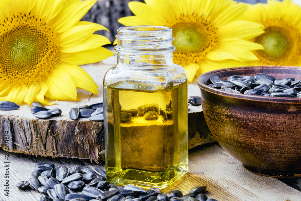Sunflowers and seeds on a wooden background near sunflower oil in a glass jar. Healthy foods and fats. Sunflowers and seeds on a wooden background near sunflower oil in a glass jar. Healthy foods and fats.