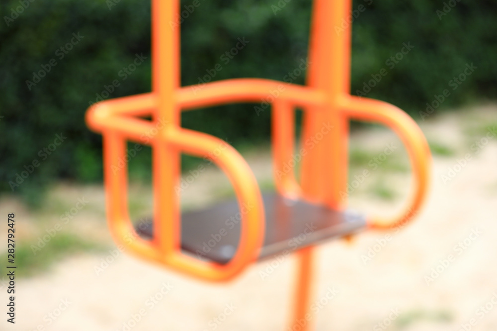 Blurred view of swing on playground in park Blurred view of swing on playground in park