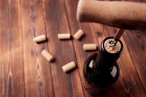 Corkscrew and bottle of wine on the board - Image