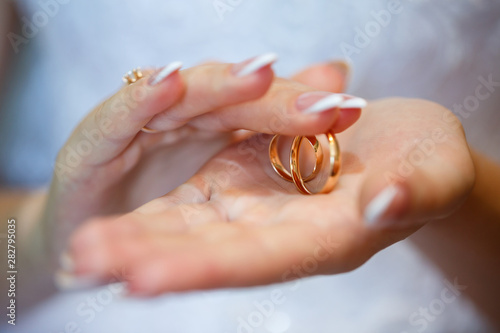 gold wedding rings in hands of newlyweds on wedding day