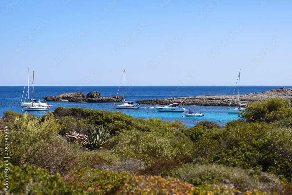 View of blue sea and boats, Binibequer beach, Menorca island, Spain