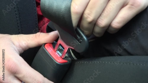 4k.UHD. Caucasian man fastening seat belt on car. Passengers sitting inside the car wearing a safety belt while waiting for the start. Safe travel is importance while traveling on car flight trip.