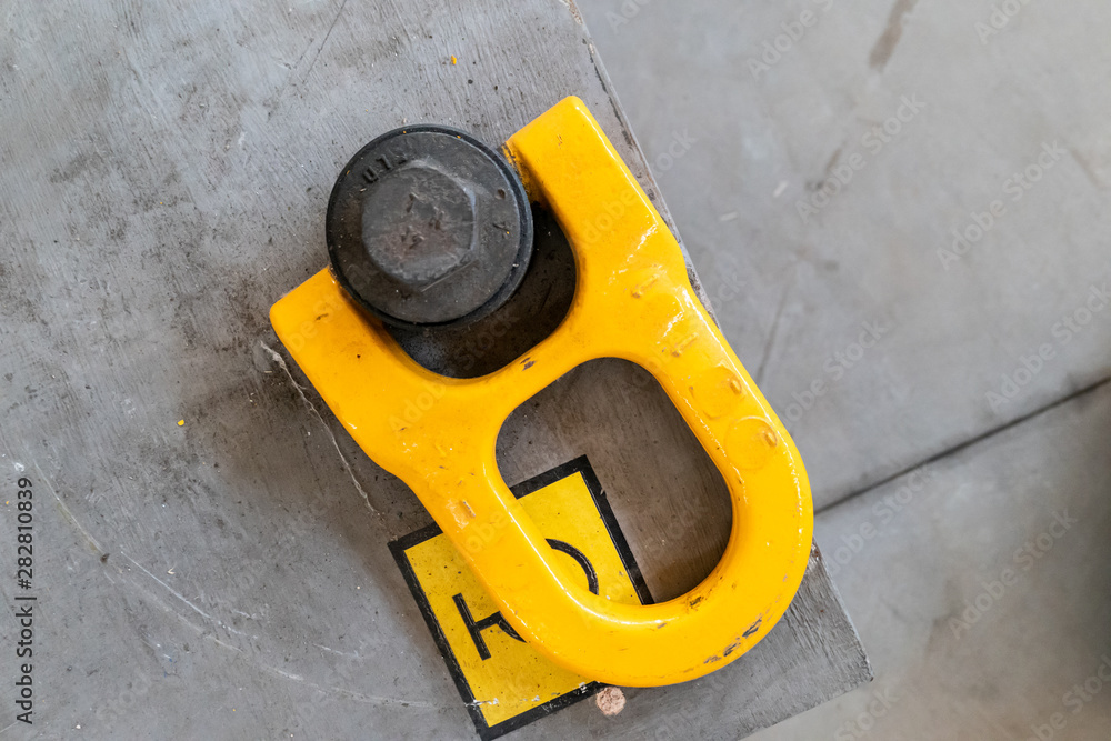 yellow eyebolt in an industrial environment for connection to a lifting hook for heavy loads