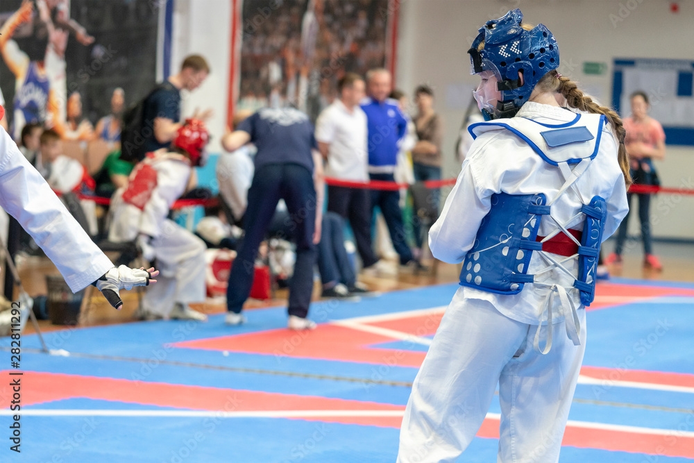  two girls in blue and red Taekwondo equipment are fighting at doyang