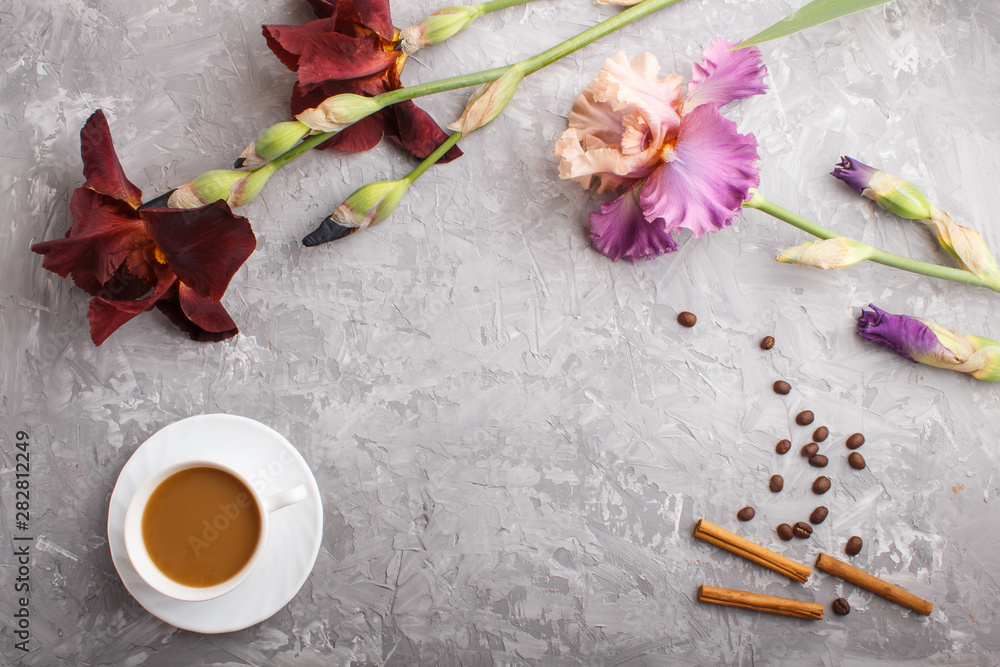 Purple and burgundy iris flowers and a cup of coffee on a gray concrete background. Purple and burgundy iris flowers and a cup of coffee on a gray concrete background.