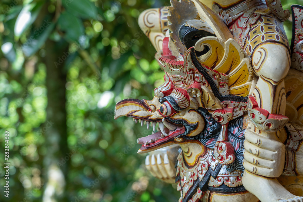 Balinese ancient colorful bird god Garuda with wings, closeup. Religious traditional statue from wood. Wooden old curved figure of Hindu god in Island Bali, Ubud, Indonesia