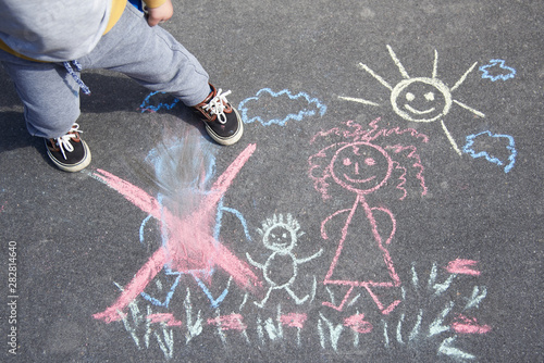 Children's drawing with chalk on the asphalt, family with no dad. Son crossed out father. Family divorce topic.