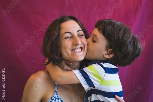 Cute boy kisses and hugs mom.
