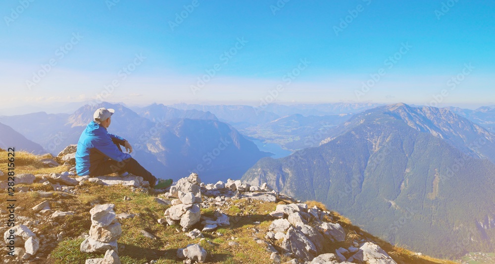 Traveler Man relaxing sitting and enjoying serene view mountains and lake landscape. Travel Lifestyle hiking concept spring autumn vacations banner. Austria Alps Dachstein Krippenstein five fingers.